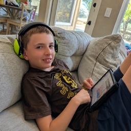 Carson, wearing noise-canceling headphones, relaxing on the couch.